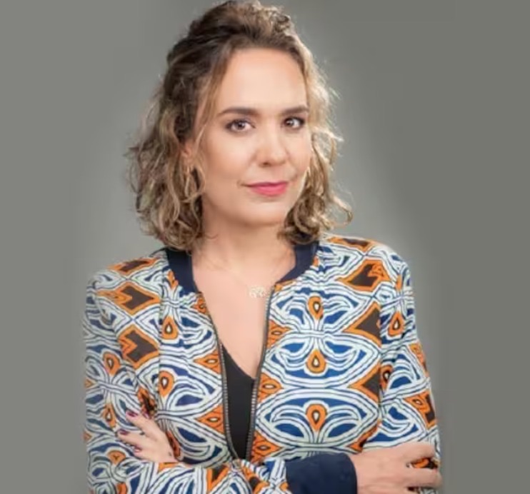 Retrato institucional de Catalina Cock, presidenta y cofundadora de Fundación Mi Sangre. Mirada serena al frente, brazos cruzados, blusa con estampado colombiano contemporáneo en tonos azul y naranja sobre blanco.